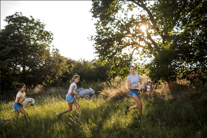 Children running with Hobby Horses through a sunny grassy field