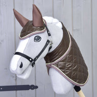 Zestaw Termo Czekolada. Hobby Horse LarDen Set Thermo Chocolate przedstawia szarego Hobby Horse z dużymi oczami, ubranego w błyszczącą brązową pikowaną derkę i pasujące nauszniki, osadzonego na kiju na tle jasnej drewnianej ściany.