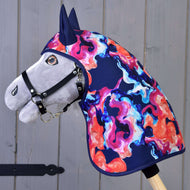 Płaszcz przeciwdeszczowy Rainbow (zimowy softshell) od Hobby Horse LarDen przedstawia pluszowego Hobby Horse z czarnym kantarem oraz wyrazistą zimową osłoną grzywy i szyi z softshellu we wzorze w kolorach niebieskim, różowym, pomarańczowym i fioletowym, pokazany na tle szarego drewna.