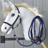 Hobby Horse - Lina do lonżowania od Hobby Horse LarDen przedstawia szarego Hobby Horse z puszystą grzywą, kreskówkowymi oczami, czarną uzdą i niebieską liną na drewnianym kiju, pokazane na tle szarej drewnianej ściany.