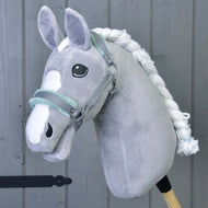 Hobby Horse LarDen Kantar szary z miętowym futerkiem — pluszowy szary dodatek do Hobby Horse z białą grzywą i znaczeniami na pysku — na tle szarych drewnianych desek.