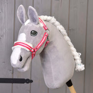 Hobby Horse LarDen „Kantar czerwony w paski z futerkiem” to szary pluszowy Hobby Horse z białą grzywą i kantarem w czerwone paski na drewnianym kiju, pokazany przed szarą drewnianą ścianą.