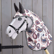 Materiałowy Hobby Horse LarDen z szarą głową, czarnym ogłowiem i kolorowym pokrowcem we wzór paisley stoi na tle drewnianych paneli, ubrany w dopasowany płaszcz przeciwdeszczowy Fairy Blue softshell dla dodatkowej ochrony i uroku.