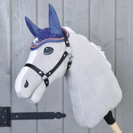 Nauszniki szydełkowane Blue Sport od Hobby Horse LarDen pokazane na pluszowym Hobby Horse z białym pyskiem i czarną uzdą, osadzonym na drewnianym kiju przed szarymi drzwiami panelowymi z czarnym zawiasem.