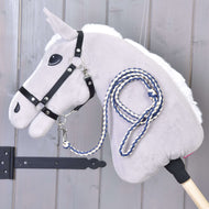 The Hobby Horse LarDen "Hobby Horse - Knitted Lead Rope Cremo-Blue" in gray, with a black bridle and blue-white knitted lead rope, hangs on a wooden wall near a black metal hinge.