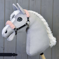 Pluszowy Hobby Horse Hobby Horse LarDen z szarym pyskiem, białą grzywą i czarnym kantarem ze starym różowym futerkiem z ekoskóry, pokazany na drewnianym tle.