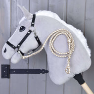 Hobby Horse - Dziana lonża Double Latte od Hobby Horse LarDen, szary konik na kiju z czarną uzdą i plecionymi wodzami, pokazany na tle szarej drewnianej ściany.