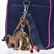Hobby Horse LarDen Brelok Horse Brown, ozdobiony kolorową chustką oraz pomarańczowymi i różowymi koralikami, przypięty do granatowej torby z różowym wykończeniem i niebieskim paskiem, idealny dla fanów Hobby Horsing.