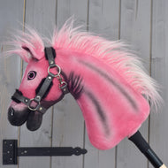 Hobby Horse LarDen Pinkie z brokatowym kantarem od Hobby Horse LarDen, edycja limitowana, osadzony na kiju i ustawiony na tle szarej drewnianej ściany.