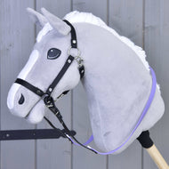 Szary pluszowy Hobby Horse Hobby Horse LarDen z białą grzywą, uzdą bezwędzidłową i Wodzami gumowanymi Jasnofioletowymi jest osadzony na drewnianym kiju na tle paneli drewnianych.