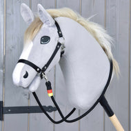 The Hobby Horse LarDen "Reins Emblem" is a gray plush hobby horse with a white mane, black bridle, and handmade polypropylene reins on a wooden stick, shown against a light wood plank background.