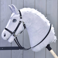 The Hobby Horse LarDen Reins Black leatherette is a gray plush hobby horse with a white mane, bitless bridle, and quality black leatherette reins on a wooden stick, shown against a gray wooden panel background.