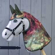 Płaszcz przeciwdeszczowy Galaxy od Hobby Horse LarDen przedstawia realistycznego szarego Hobby Horse z czarnym ogłowiem oraz marmurkową osłoną głowy i szyi w stylu całorocznego płaszcza przeciwdeszczowego w kolorach zielonym, czerwonym i kremowym, pokazany na drewnianym tle.