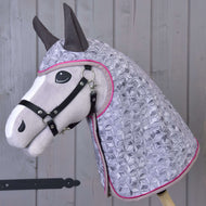 Hobby Horse LarDen Raincoat Valentine, pluszowy Hobby Horse z czarną uzdą i pikowanym jasnofioletowym kapturem z geometrycznym wzorem i różową lamówką, pokazany na tle drewnianych paneli.