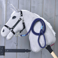 Hobby Horse - sznurkowy pasek Blues Hobby Horse LarDen: pluszowy szary Hobby Horse z czarną uzdą i niebieską smyczą na drewnianym kiju, pokazany na tle szarej drewnianej ściany.