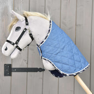 Pluszowy Hobby Horse na drewnianym kiju nosi Derkę Piękne Jeansy od Hobby Horse LarDen i czarny kantar, ustawiony na tle jasnej drewnianej ściany dla dodatkowej ochrony.