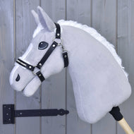 Szary Hobby Horse z białą grzywą i czarną uzdą jest osadzony na drewnianym kiju i ma założony Hobby Horse LarDen Kantar ze sztucznym futrem - skóra ekologiczna Espresso, ustawiony przed jasnoszarą drewnianą ścianą z widocznym po lewej czarnym zawiasem.