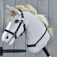 Cordeo Chocolate od Hobby Horse LarDen przedstawia szarego pluszowego Hobby Horse z czarną uzdą i kremową sznurkową grzywą na drewnianym kiju, pokazane na tle szarych drewnianych paneli.