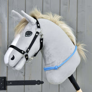 Hobby Horse LarDen "Cordeo Sky" to szary pluszowy Hobby Horse z białą grzywą, czarną uzdą i niebieską liną, zaprojektowany do jazdy z uzdą lub bez niej. Stoi na drewnianym tle i ma przyjazny wyraz.