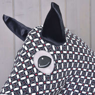 A close-up of the Hobby Horse LarDen protective suit DeLuxe (Lycra) shows its washable black and white geometric lycra fabric, large black ears, and stitched eye against a light wooden background.