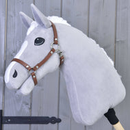 Szary pluszowy Hobby Horse LarDen z białą grzywą i znaczeniami na nosie, z brązowym kantarem ze skóry ekologicznej, osadzony na drewnianym kiju i pokazany na tle szarej drewnianej ściany.