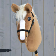 Hobby Horse Star z czarnym kantarem od Hobby Horse LarDen ma karmelowe umaszczenie, białą strzałkę, kremową grzywę i jest pokazany z czarnym kantarem na tle szarego drewna.