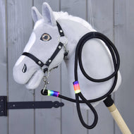 Hobby Horse - Uwiąz Rainbow od Hobby Horse LarDen, szary Hobby Horse z białą grzywą, czarną uzdą, wodzami i uwiązem z tęczową taśmą wokół szyi, pokazany na tle drewnianych paneli.