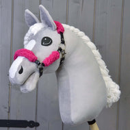 Hobby Horse LarDen przedstawia ręcznie wykonanego szarego Hobby Horse z białą grzywą i łatką na pysku, noszącego Czarny kantar z pełnym różowym futerkiem - skóra ekologiczna, pokazanym na drewnianym tle.