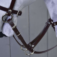 Close-up of the Martingale brown by Hobby Horse LarDen, featuring a brown leather bridle with metal buckles and rings on a light grey model horse head, set against a grey wooden background.