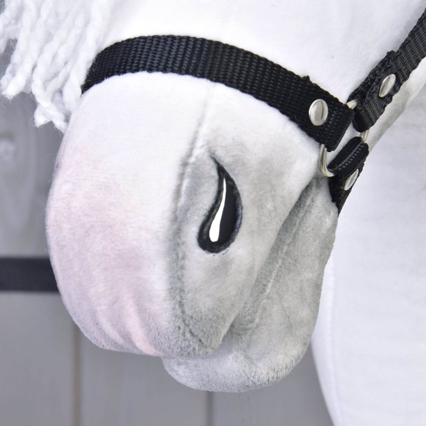 Zbliżenie na Hobby Horse Elektra z czarnym kantarem od Hobby Horse LarDen, z pluszowym białym pyskiem, czarnym kantarem, haftowanym czarnym detalem w kształcie łzy, miękką fakturą, białą grzywą z włóczki oraz cechami inspirowanymi klaczą lipicańską.