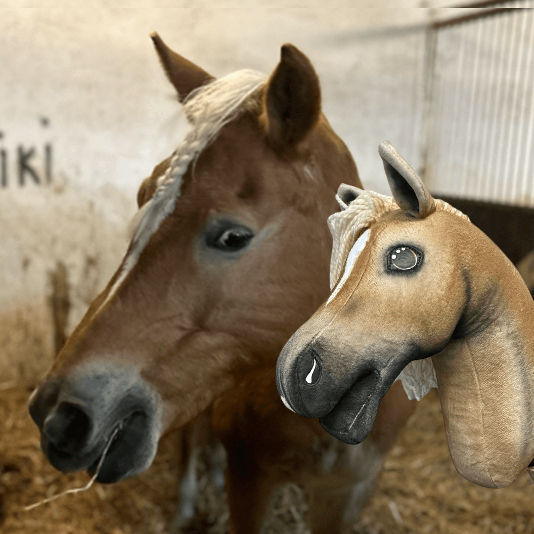 A brown horse with a white mane stands in a stable next to the Hobby Horse LarDen "Hobby Horse based on your photo" plush, which features a matching design. The background displays stable bars and a wall.