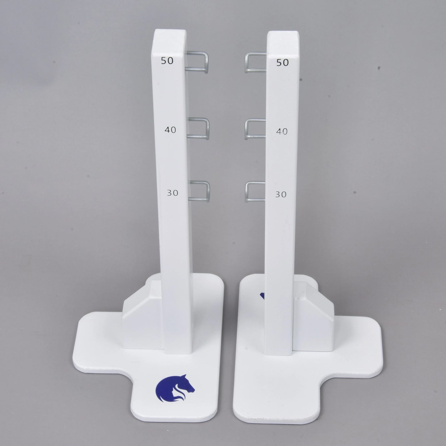 The Hobby Horse LarDen Jump 50 cm / 20 inch features two white vertical stands with measurement marks at 30, 40, and 50 cm, metal hooks on each side, a blue horse logo on sturdy bases—ideal for adjustable hobby horsing jumps indoors or outdoors.