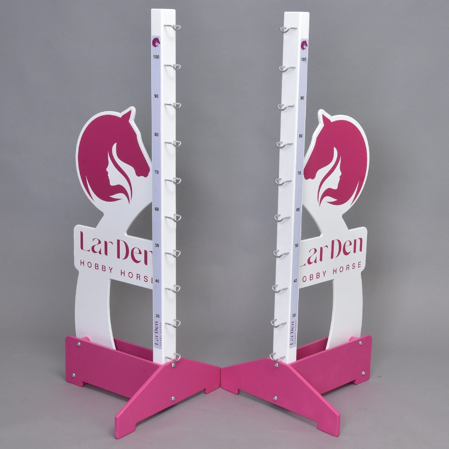 Two pink and white Hobby Horse LarDen jump 110 cm / 43 inch stands with horse head designs, adjustable height markings, and metal cup holders stand on a gray background. "LarDen HOBBY HORSE" is printed on the base.