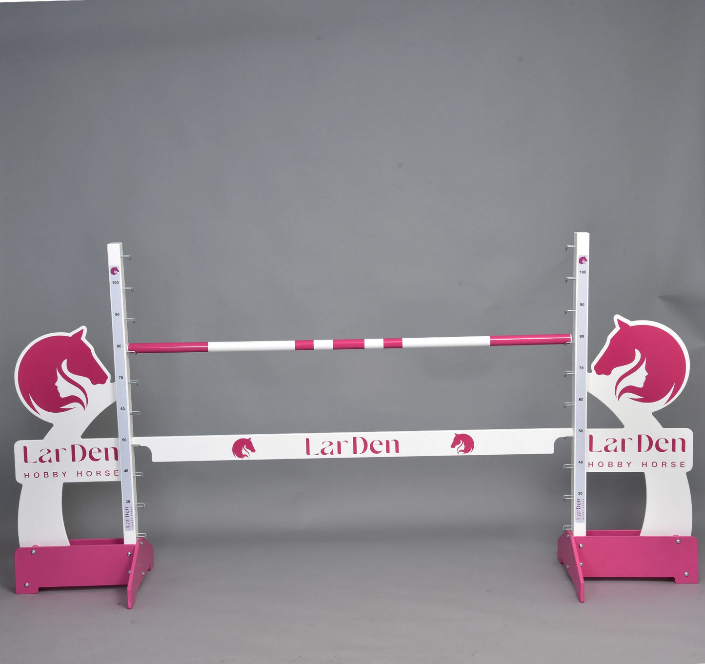 The Hobby Horse LarDen jump 110 cm / 43 inch features pink and white bars, horse head silhouettes, and adjustable height—ideal for hobby horse riding. Brand: Hobby Horse LarDen. Set against a plain gray background.