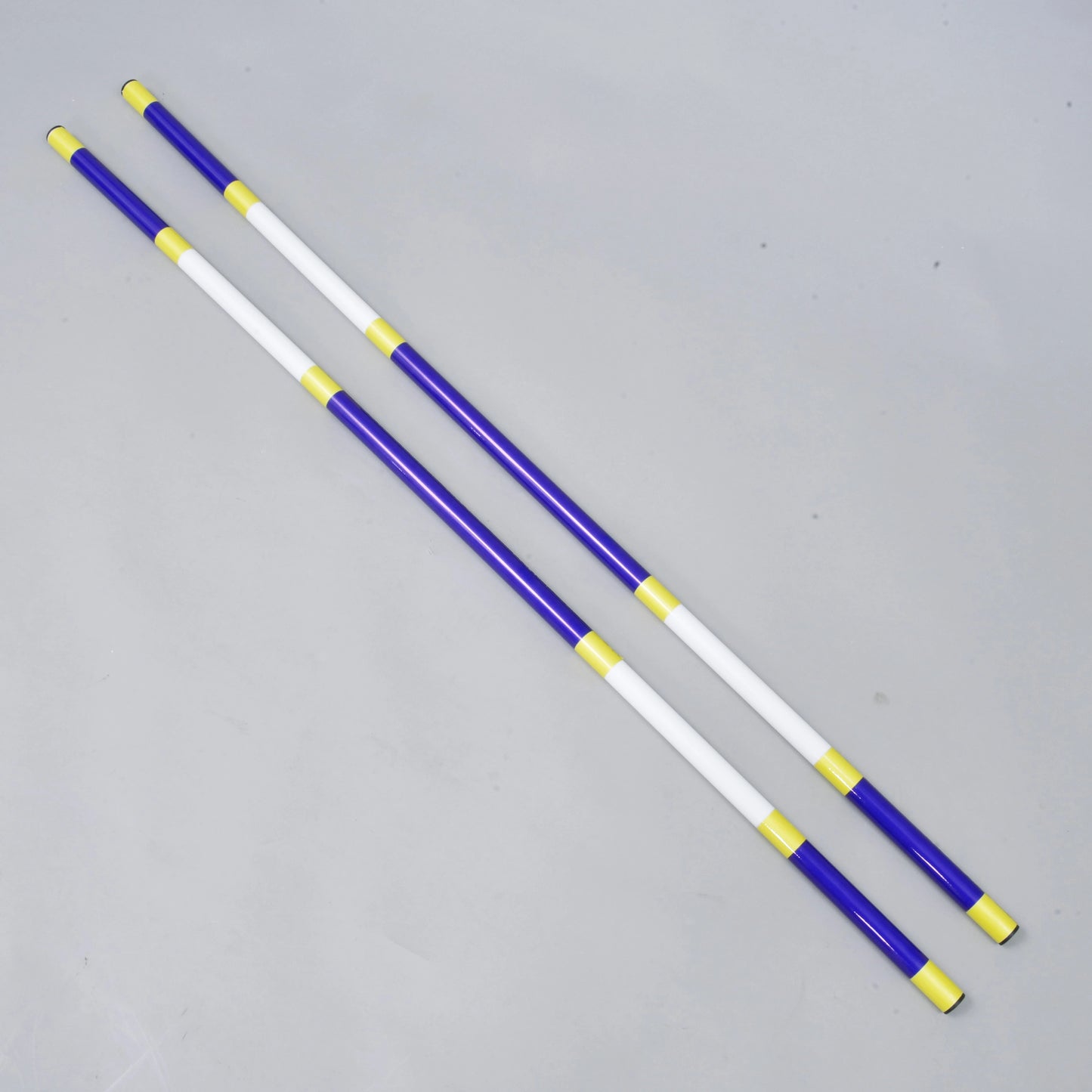 Drągi do skoków niebiesko-białe 2 szt. od Hobby Horse LarDen, dwa lekkie drągi o średnicy 32 mm z powlekanego PVC leżą równolegle na jasnoszarej powierzchni.