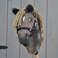 The Hobby Horse LarDen Avalon, size XS, features a brown plush head, black halter, and yarn mane inspired by an English Warmblood sport horse, beautifully displayed against a wooden background.