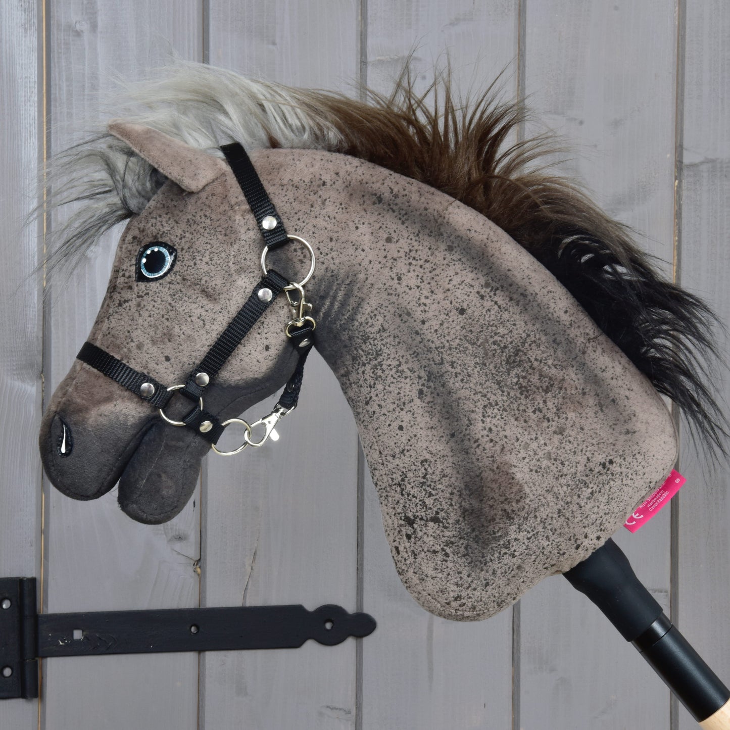The Hobby Horse LarDen Bolero with Black Halter (size S) features a plush stallion head with a realistic mane, mounted on a stick and displayed against a light gray wooden wall.