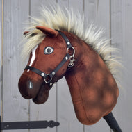 Zbliżenie na Hobby Horse LarDen „Hobby Horse Cinnamon z czarnym kantarem - rozmiar S”, z brązowym pluszowym wykończeniem, puszystą grzywą i czarnym kantarem, przypominający dumnego ogiera, na drewnianym tle.