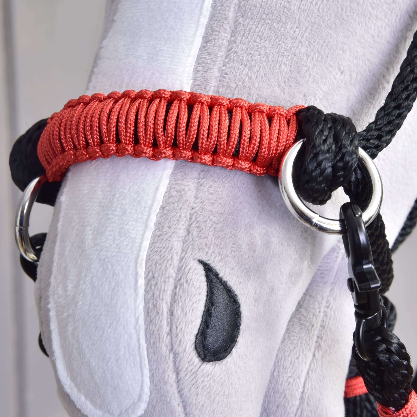 Close-up of a plush toy horse’s head with a red and black halter, stitched black eye, and gray-white fabric, featuring the Hobby Horse LarDen Rope set Spark, crafted from durable polypropylene as a unique handmade accessory.