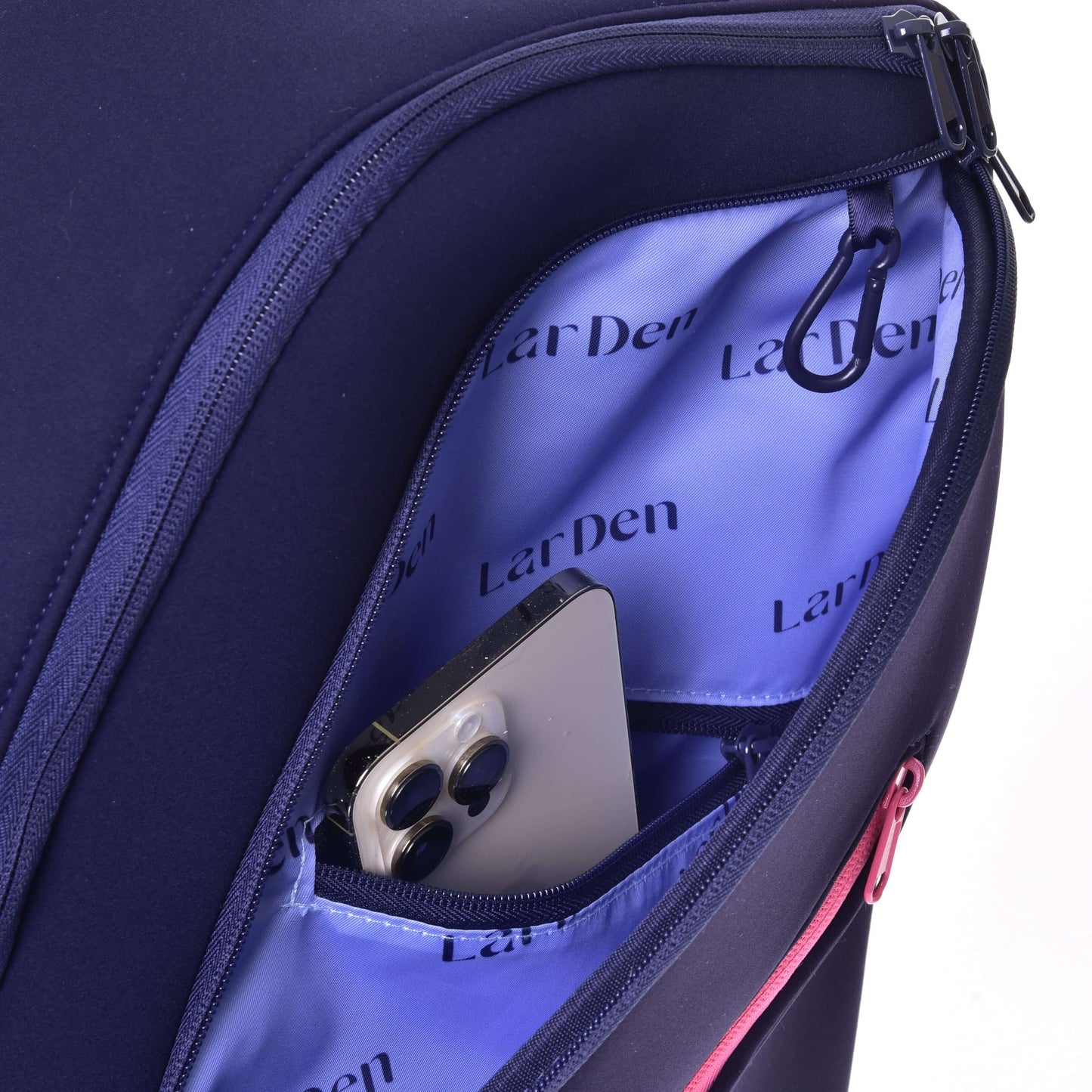 A close-up of an open Hobby Horse Backpack LarDen by Hobby Horse LarDen in navy blue neoprene with a purple interior. Padded straps and a smartphone with three rear cameras are partially visible in the inner pocket.