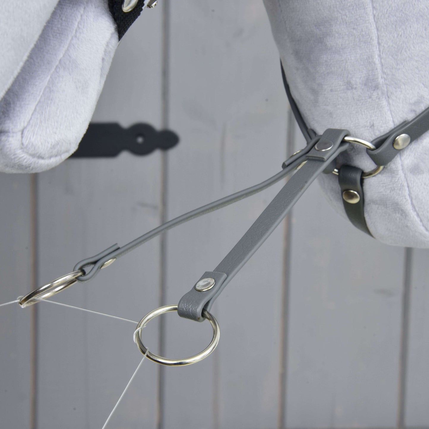 Close-up of the Martingale dark grey by Hobby Horse LarDen, featuring grey leather straps and a leatherette martingale with metal rings on a light grey stuffed horse head, displayed against a wooden background.