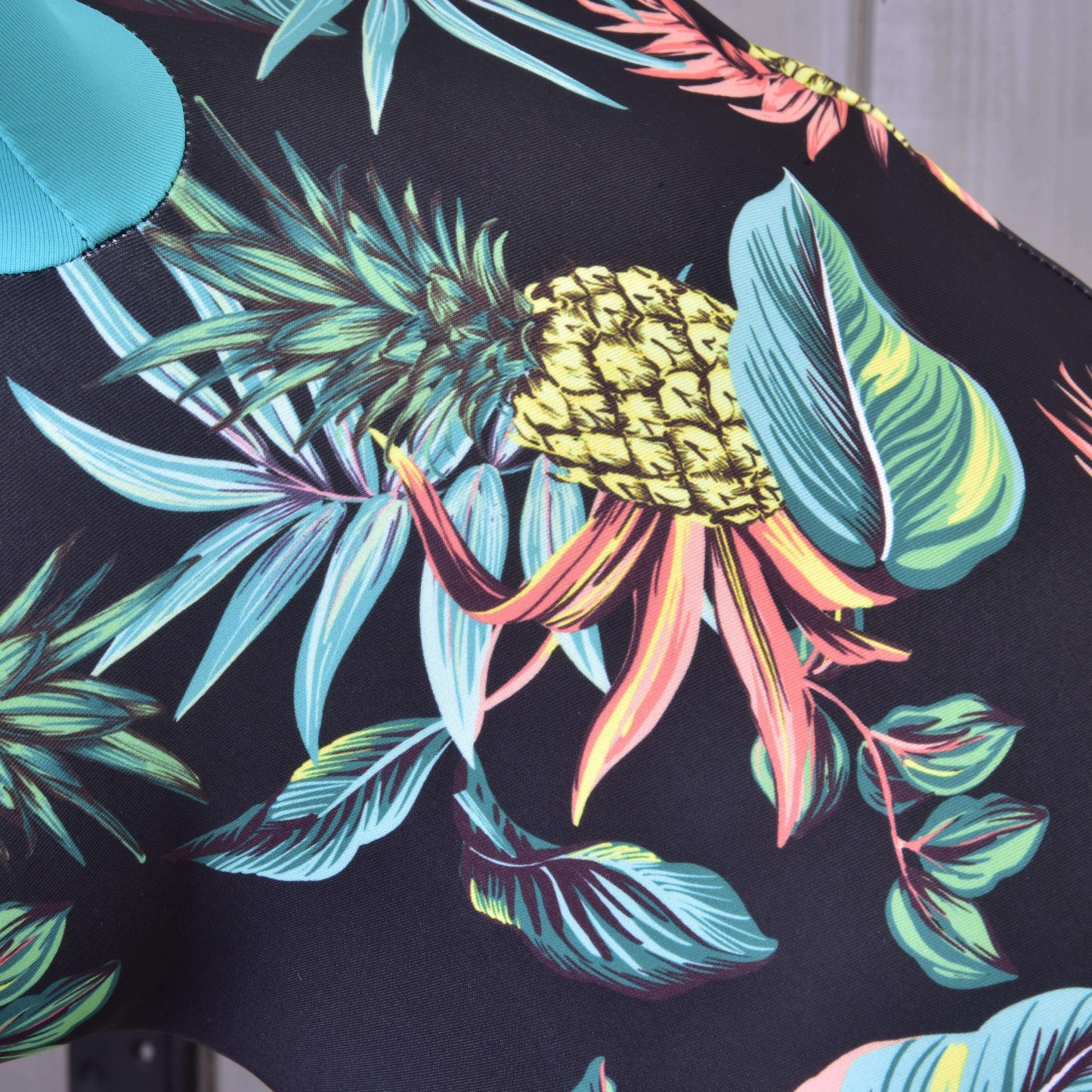 Close-up of Hobby Horse LarDen's "Hobby Horse Protective Suit Pineapple (Lycra)," made from PES and Lycra, with vibrant pineapples, green leaves, and foliage on black—perfect for crafting a stylish protective suit.