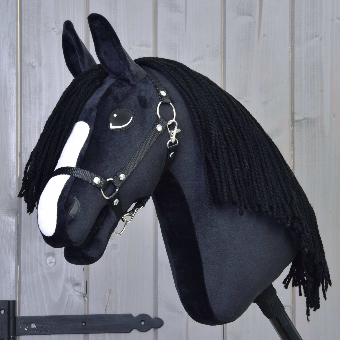 The Hobby Horse LarDen "Hobby Horse Freya with Black Halter" features black fabric, a white nose stripe, and a long black yarn mane inspired by the Irish Cob, shown on a light wooden background.