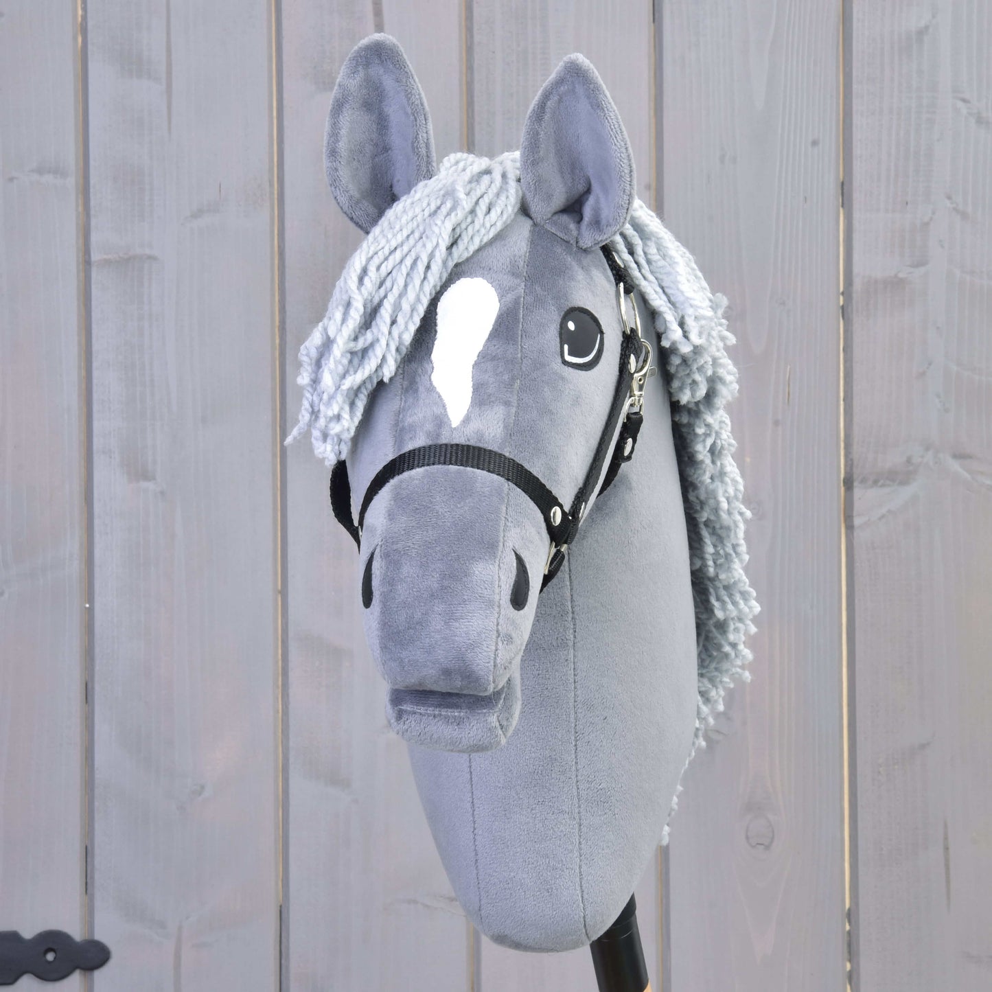 Hobby Horse LarDen's Grace, a gray Dutch Warmblood hobby horse with black halter and gray yarn mane, is shown in front of a light wooden fence.
