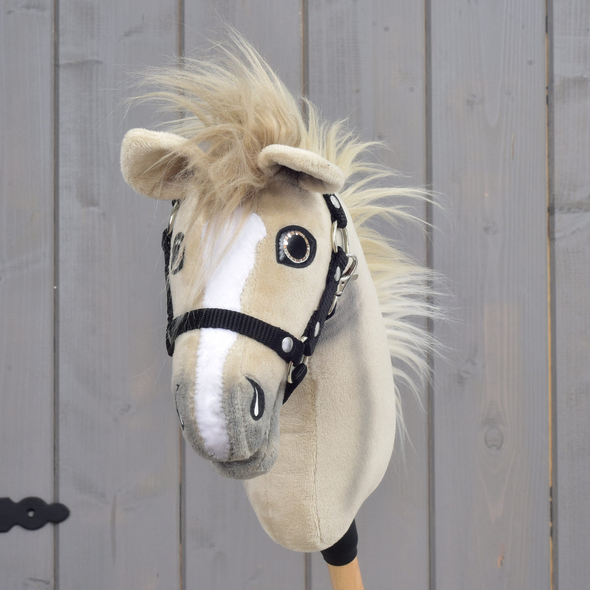 The Hobby Horse LarDen “Hobby Horse Ivory Dream with Black Halter” in size XS features a beige and white plush design with button eyes and a fluffy mane, showcased against a light wooden background.