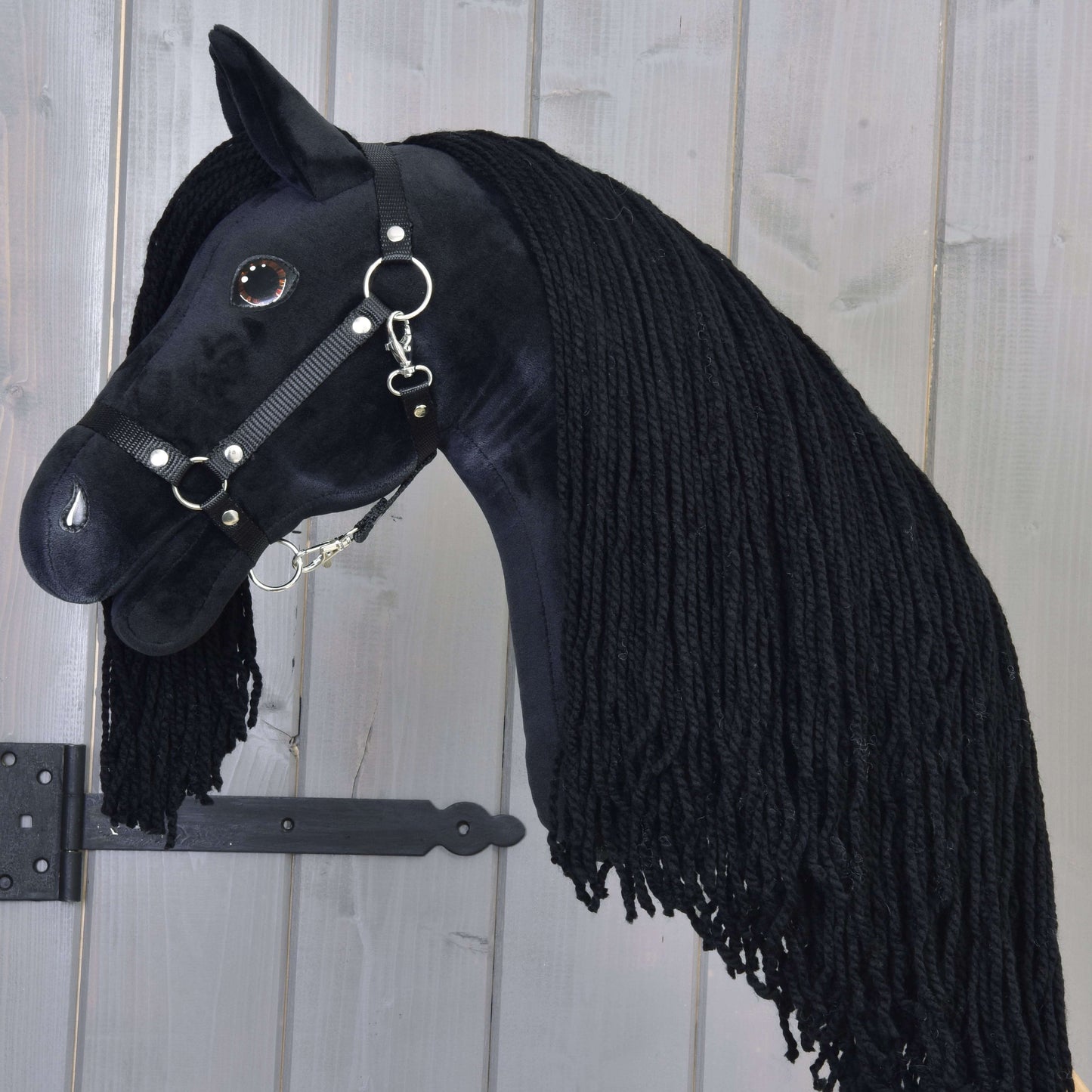 The Hobby Horse LarDen "Hobby Horse Maximus with Black Halter" features a handmade black stallion design, thick black yarn mane, and bridle, presented against a light wooden background.