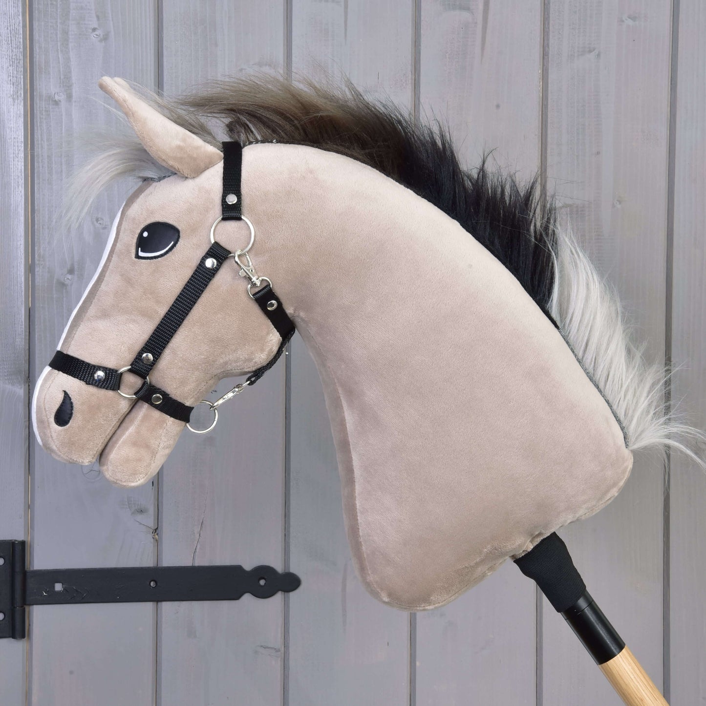 Plush hobby horse Piccolino with a sideview and a bridle against a wooden background