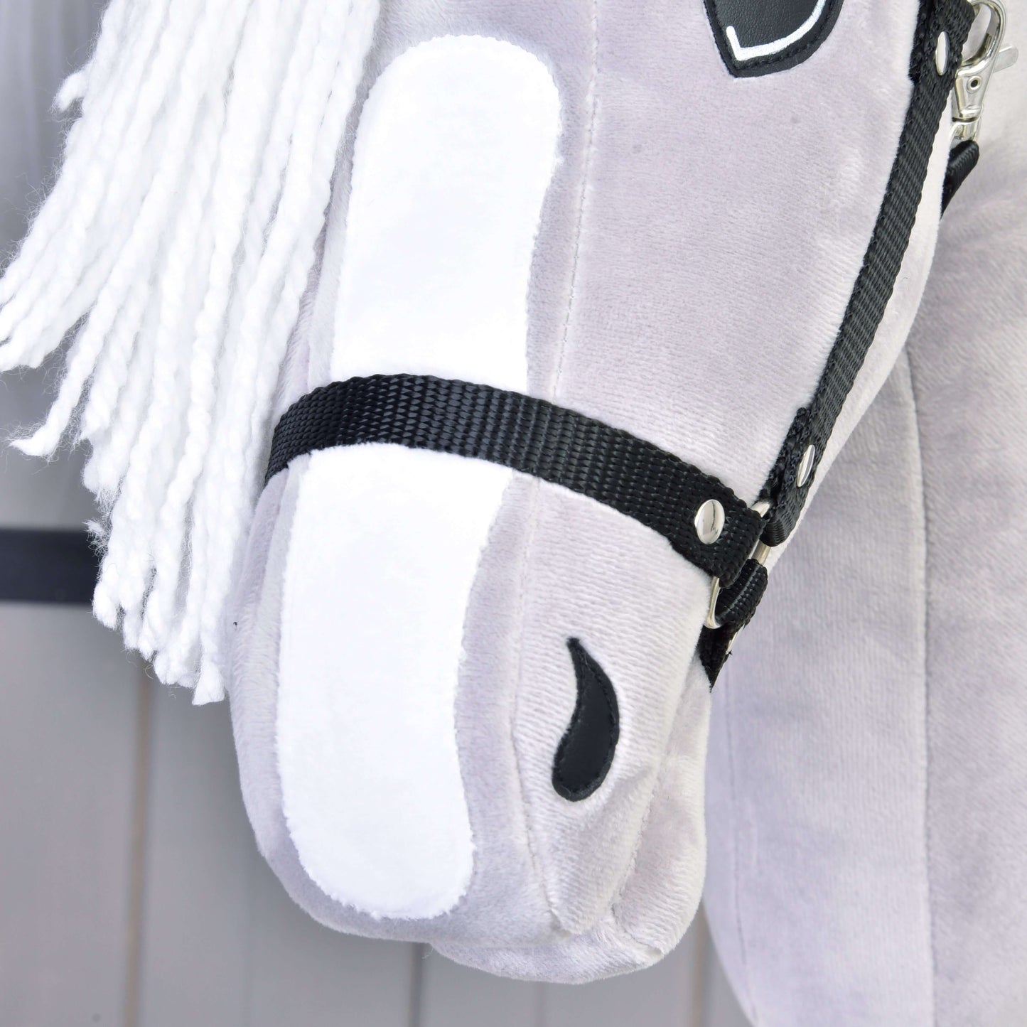 A close-up of Hobby Horse LarDen's gray plush "Hobby Horse Popcorn with Black Halter," inspired by an English Thoroughbred, features a white yarn mane, black halter, and soft stitched details, including a black nostril.