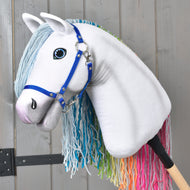 Bajkowy Hobby Horse Rainbow New od Hobby Horse LarDen z niebieskimi wodzami, jasnoniebieską grzywą z włóczki i tęczową grzywą z włóczki jako ogonem na tle szarego drewna