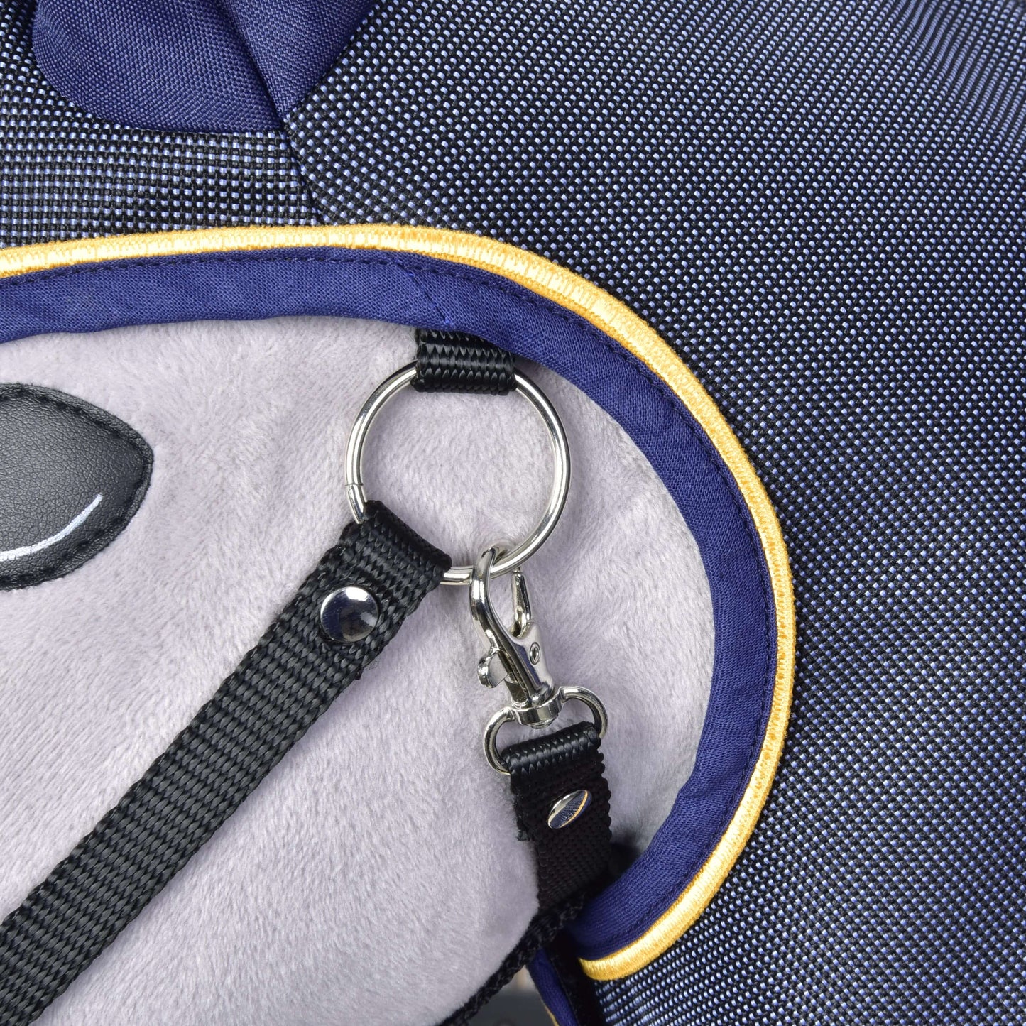 Close-up of a fabric bag with plush panel, navy blue trim, yellow piping, and metal D-ring clasp securing a black strap—ideal for carrying your Hobby Horse LarDen Raincoat Crone or hobby horse accessories on every adventure.